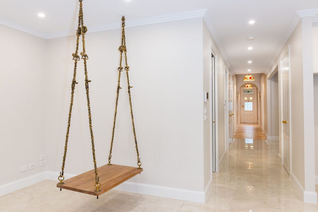 A wooden swing hanging in a hallway