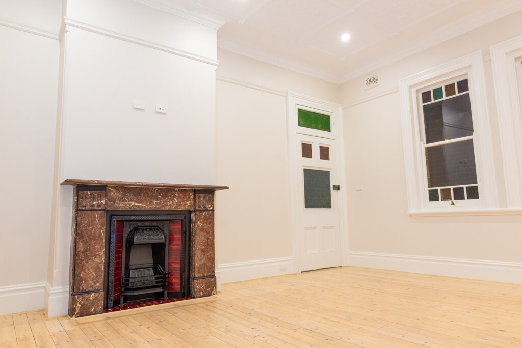 An empty white room with a fireplace and windows