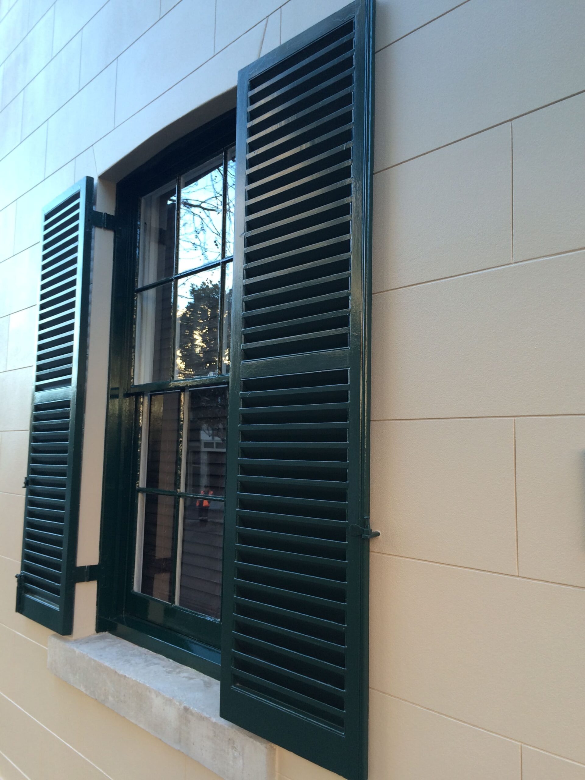 Glass window with black shutters on a white wall