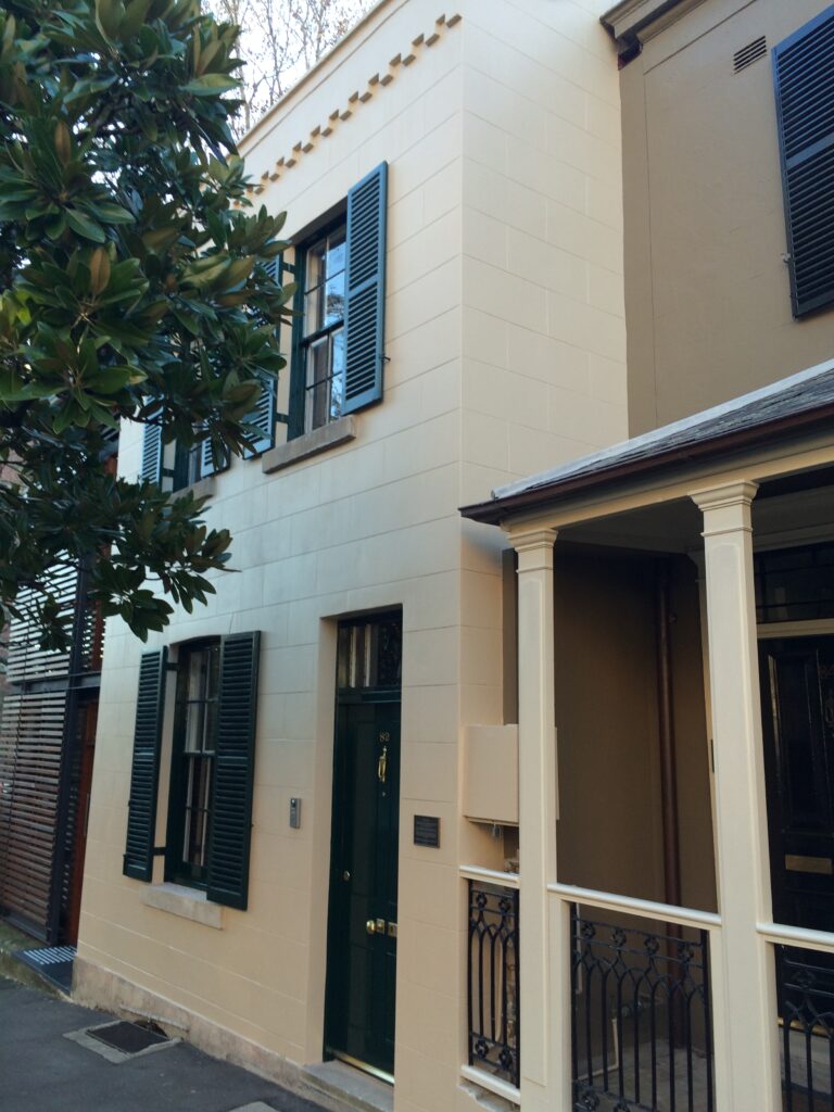 A heritage style home with black shutters and a door