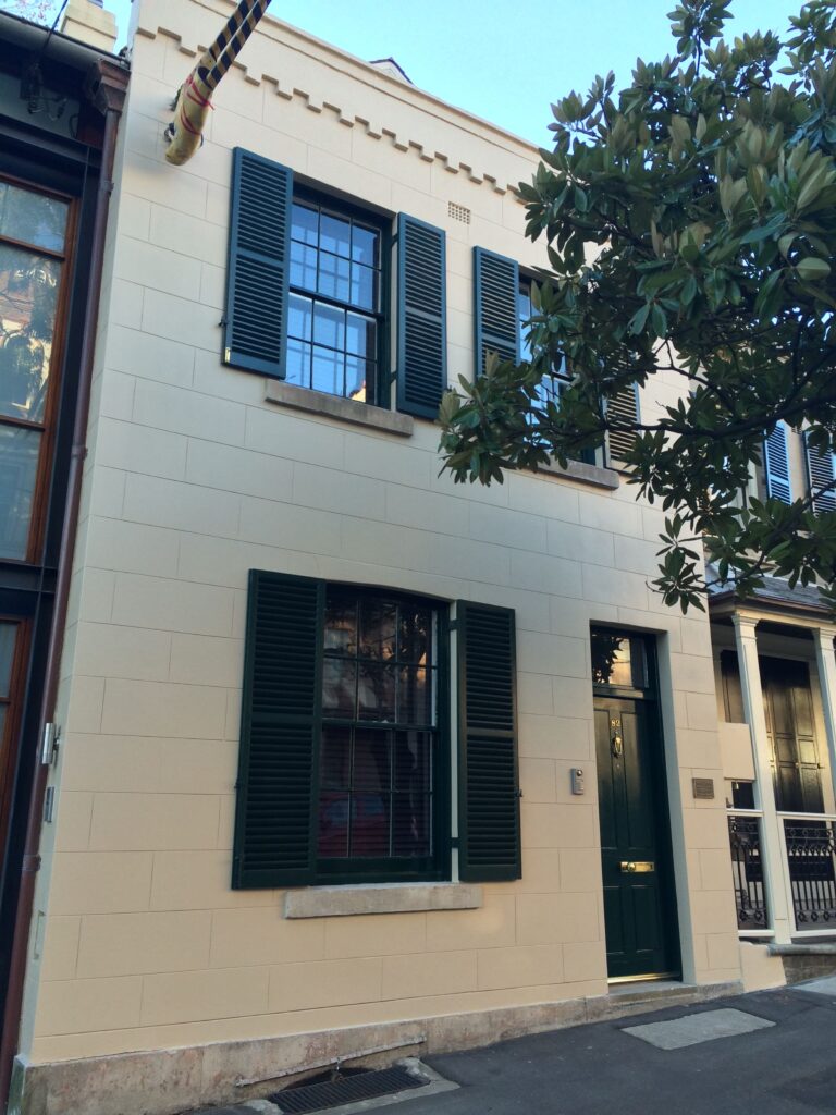 A white remedial building in Sydney and a tree in front of it