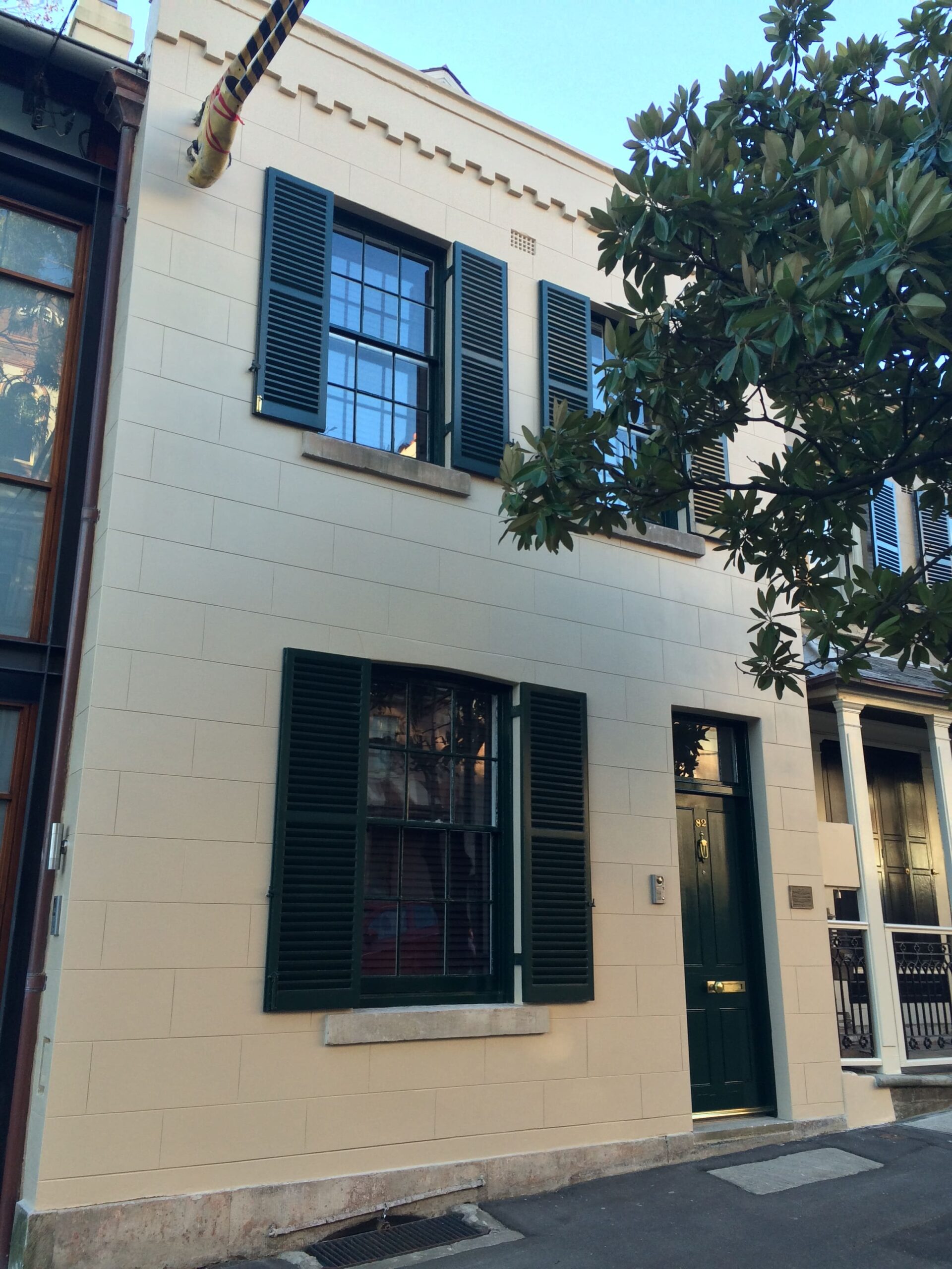 A white remedial building in Sydney and a tree in front of it