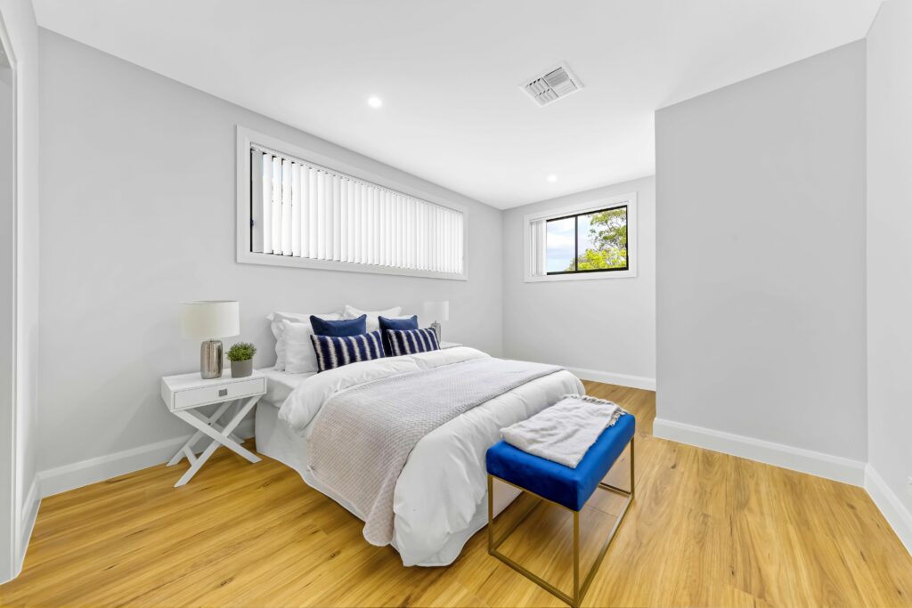 White bedroom with bed and hardwood flooring